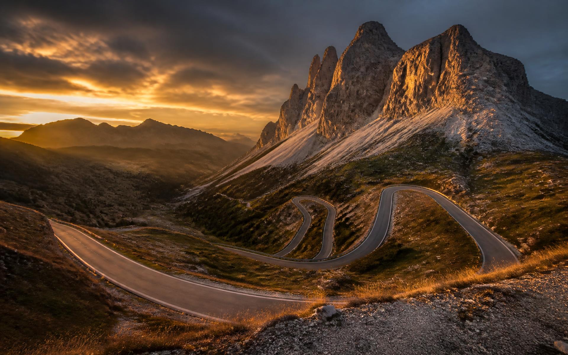 Empty mountain road winding through the Dolomites at dusk